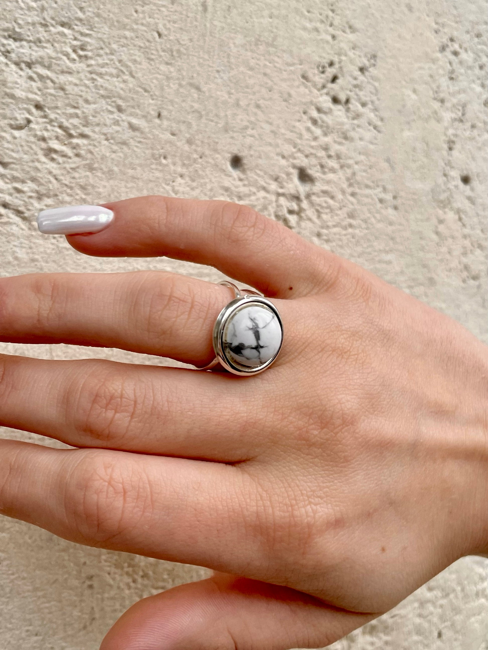 Bague THÉA, en argent et pierre d'Howlite, portée sur une main de femme.