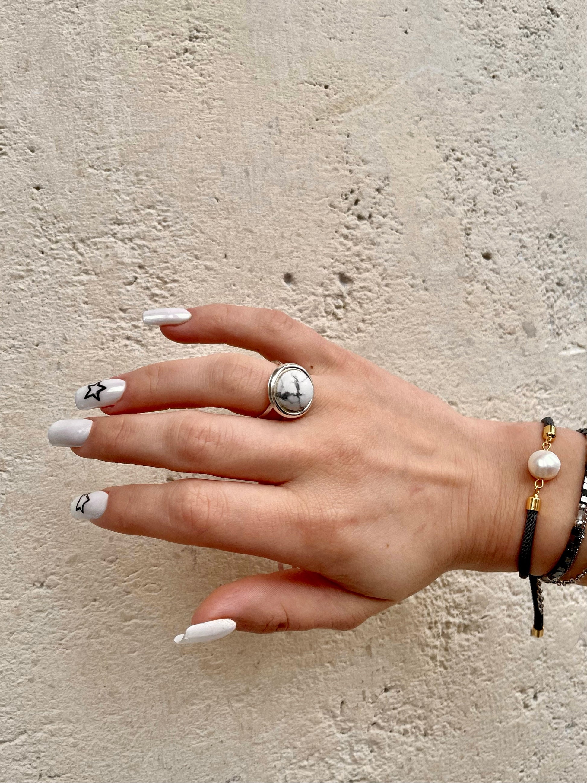 Bague THÉA, en argent et pierre d'Howlite, portée sur une main de femme.