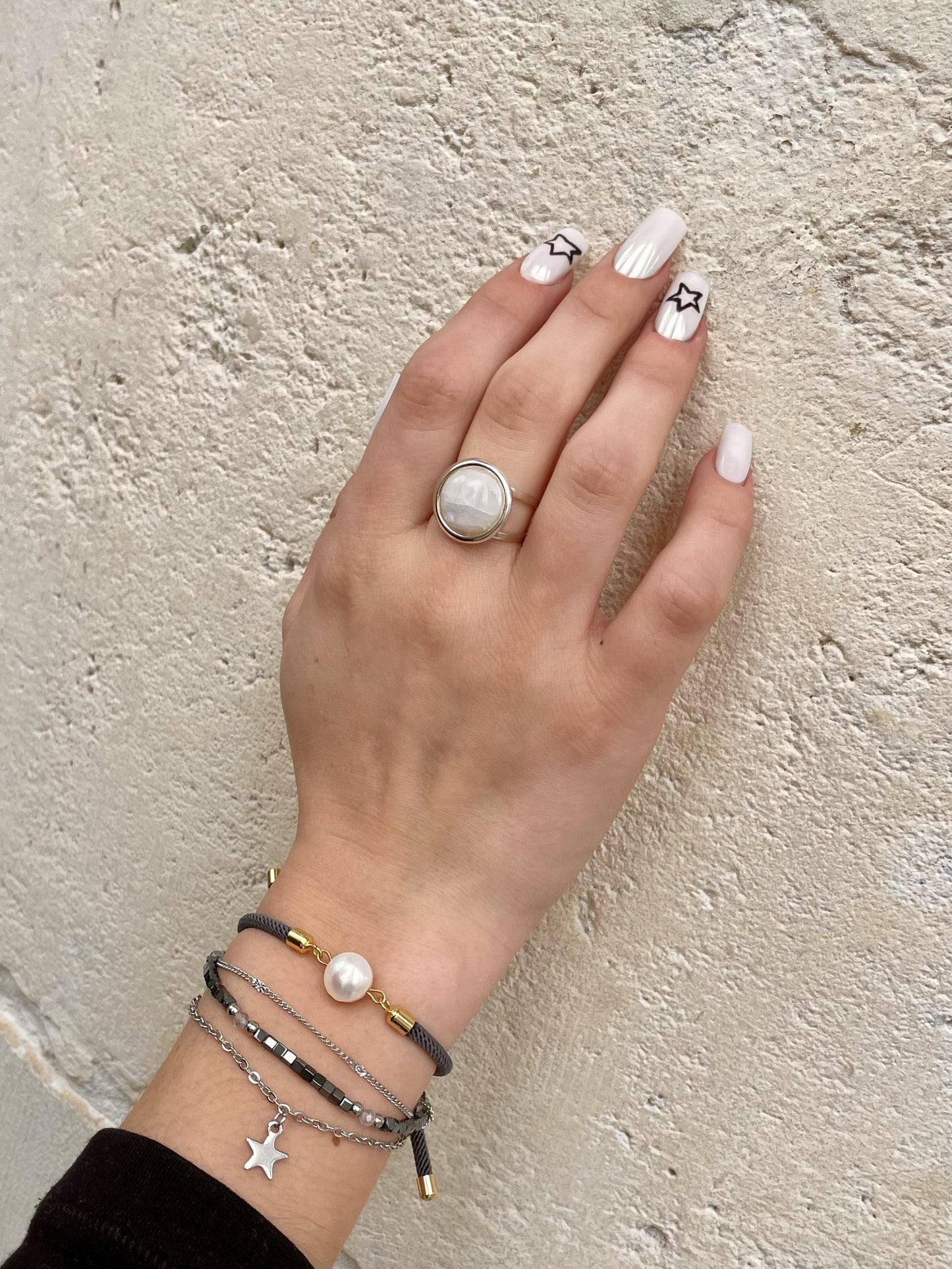 Bague THÉA, en argent et pierre de Lune, portée sur une main de femme.