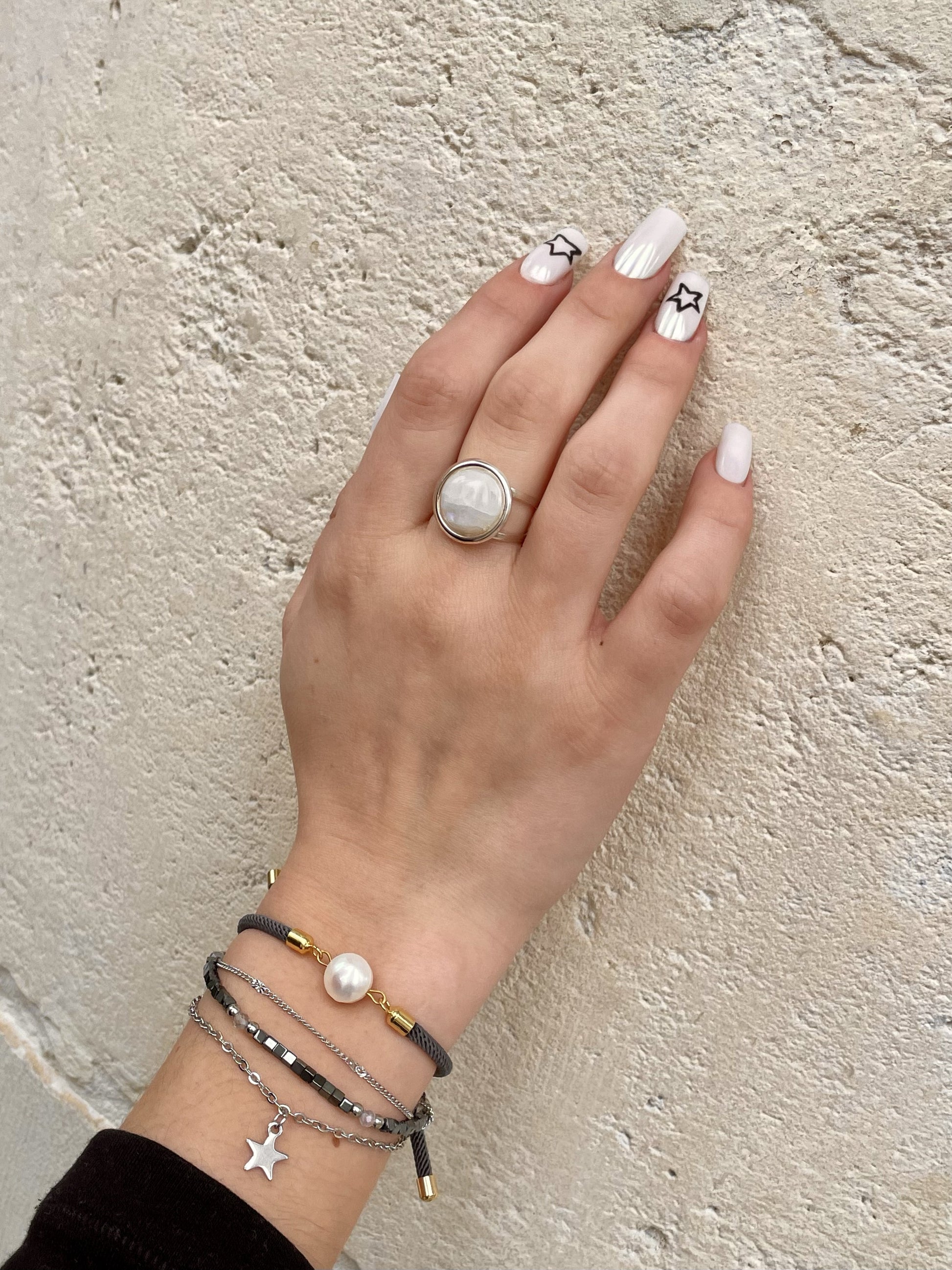 Bague THÉA, en argent et pierre de Lune, portée sur une main de femme.
