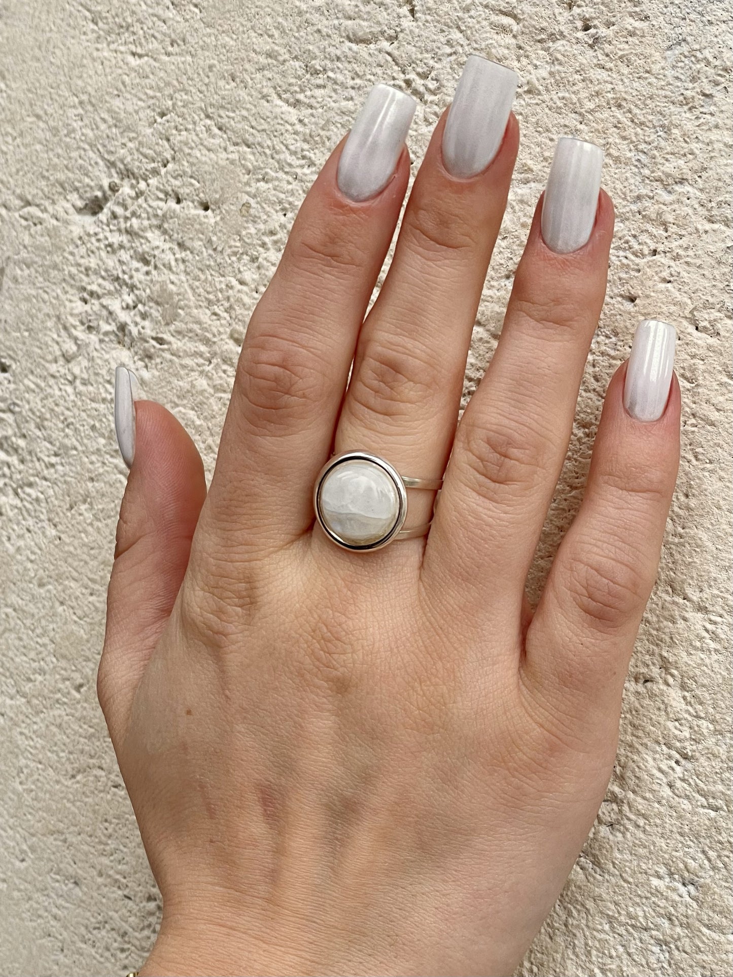 Bague THÉA, en argent et pierre de Lune, portée sur une main de femme.