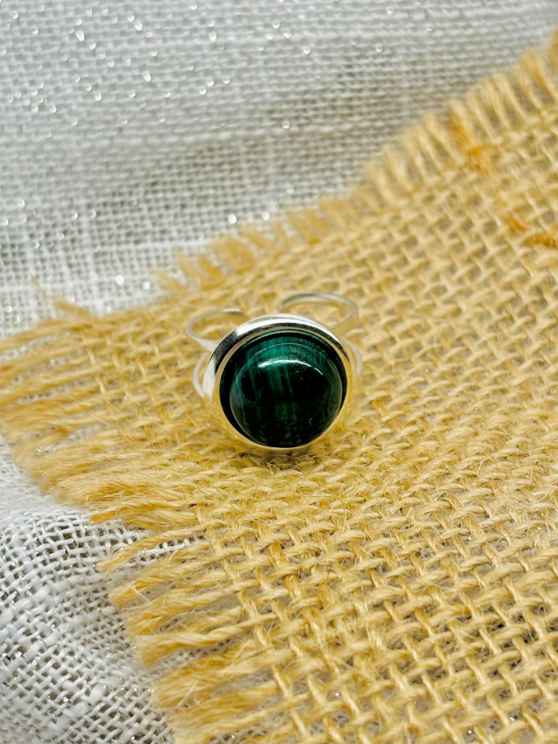 Bague THÉA, en argent et pierre de Malachite, sur un fond en lin et toile de jute.