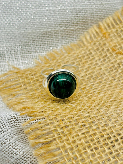 Bague THÉA, en argent et pierre de Malachite, sur un fond en lin et toile de jute.