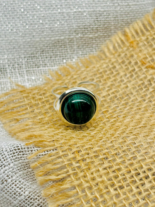 Bague THÉA, en argent et pierre de Malachite, sur un fond en lin et toile de jute.