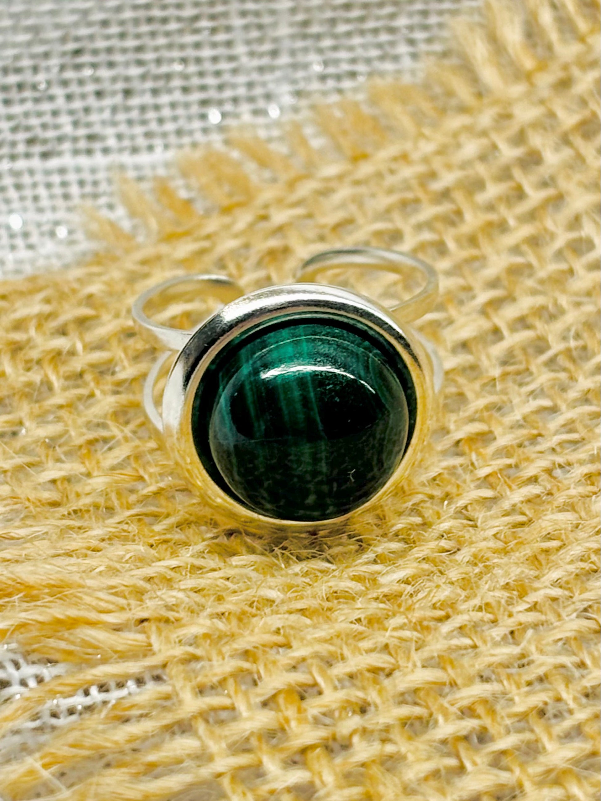 Bague THÉA, en argent et pierre de Malachite, sur un fond en lin et toile de jute.