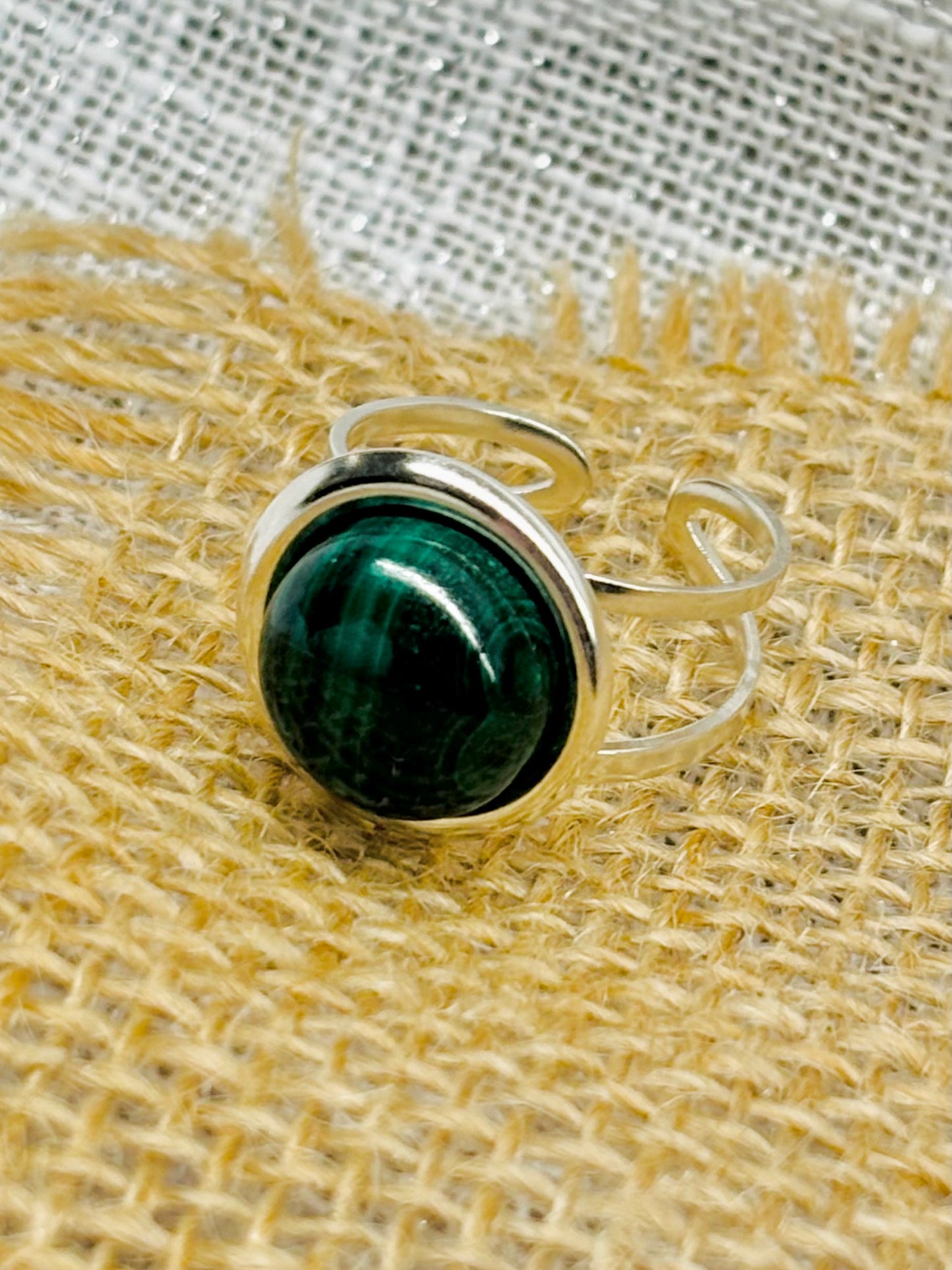 Bague THÉA, en argent et pierre de Malachite, sur un fond en lin et toile de jute.