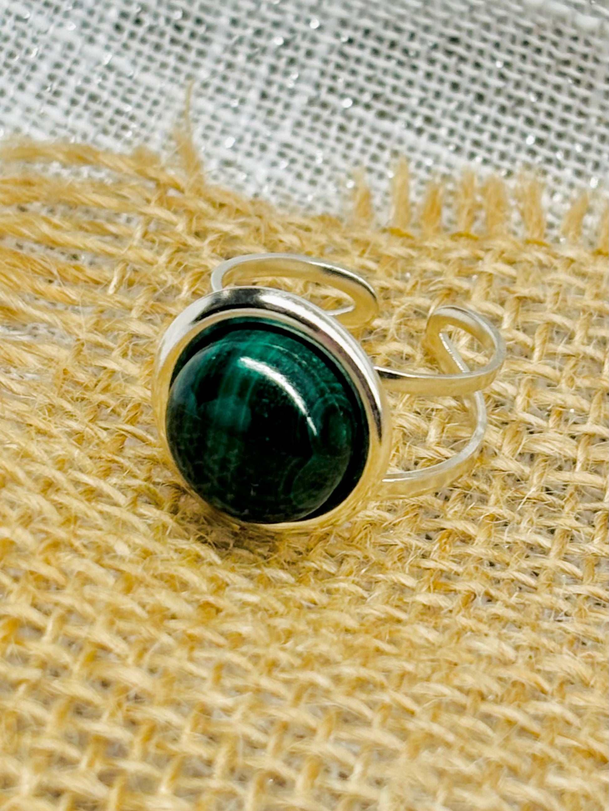 Bague THÉA, en argent et pierre de Malachite, sur un fond en lin et toile de jute.