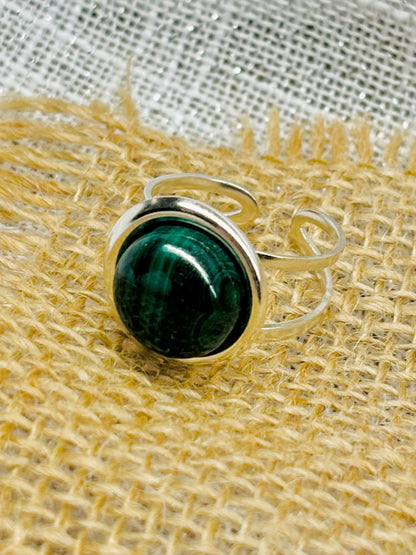 Bague THÉA, en argent et pierre de Malachite, sur un fond en lin et toile de jute.