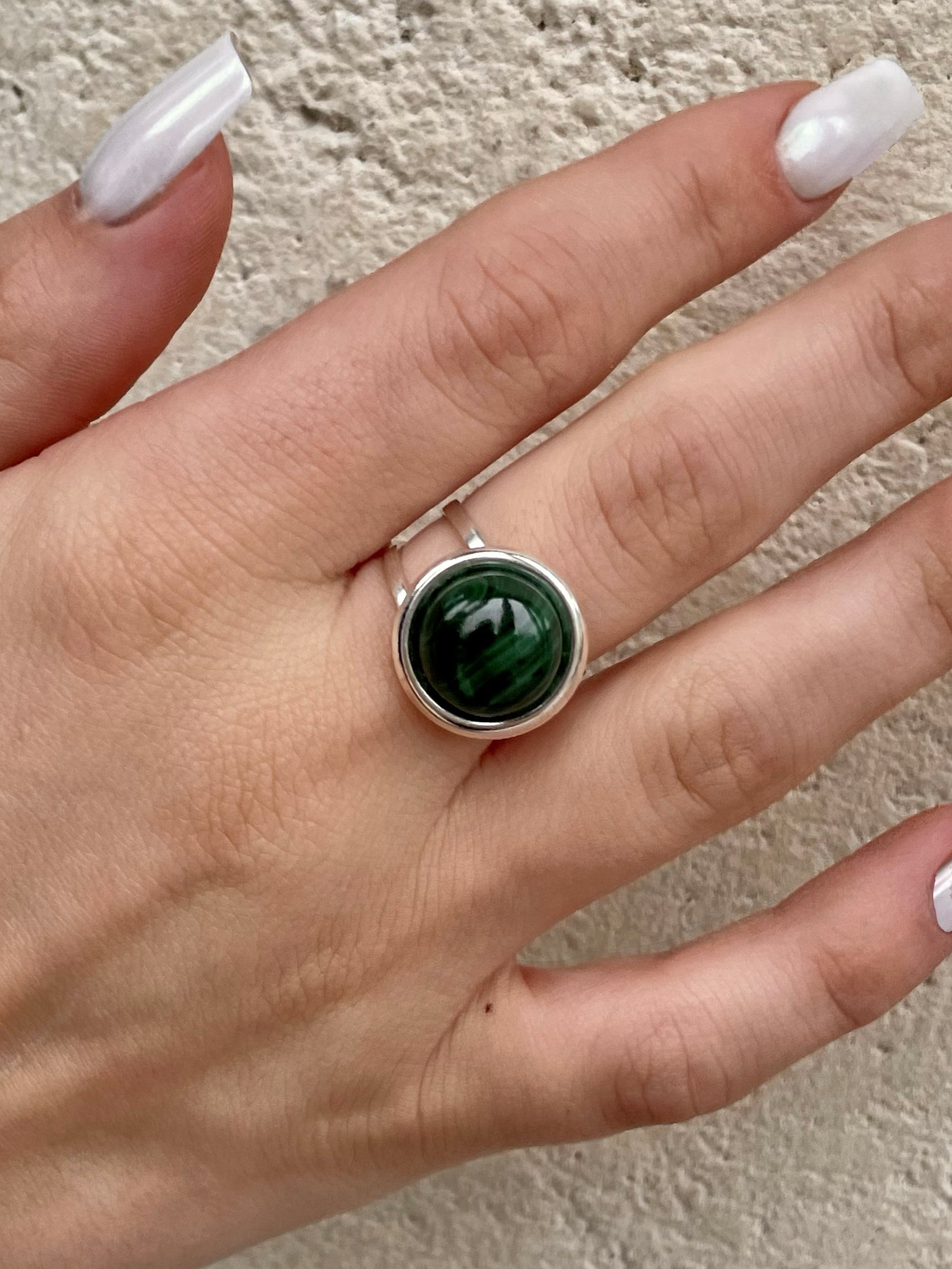 Bague THÉA, en argent et pierre de Malachite, portée sur une main de femme.