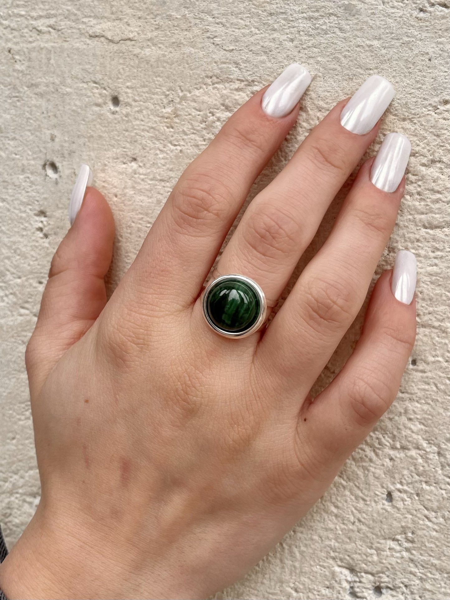 Bague THÉA, en argent et pierre de Malachite, portée sur une main de femme.