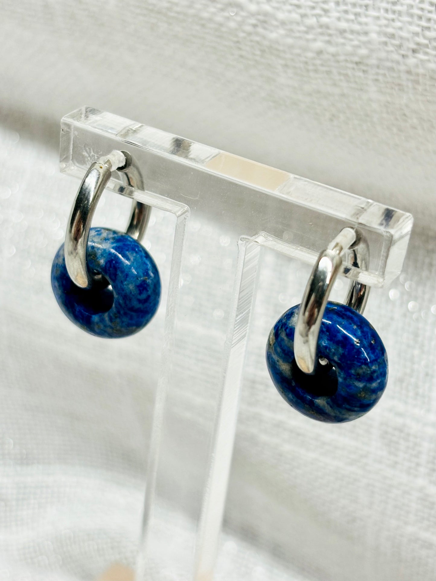 Boucles d'oreille THELMA, avec pierre de Lapis-Lazuli, exposées sur un fond en lin.