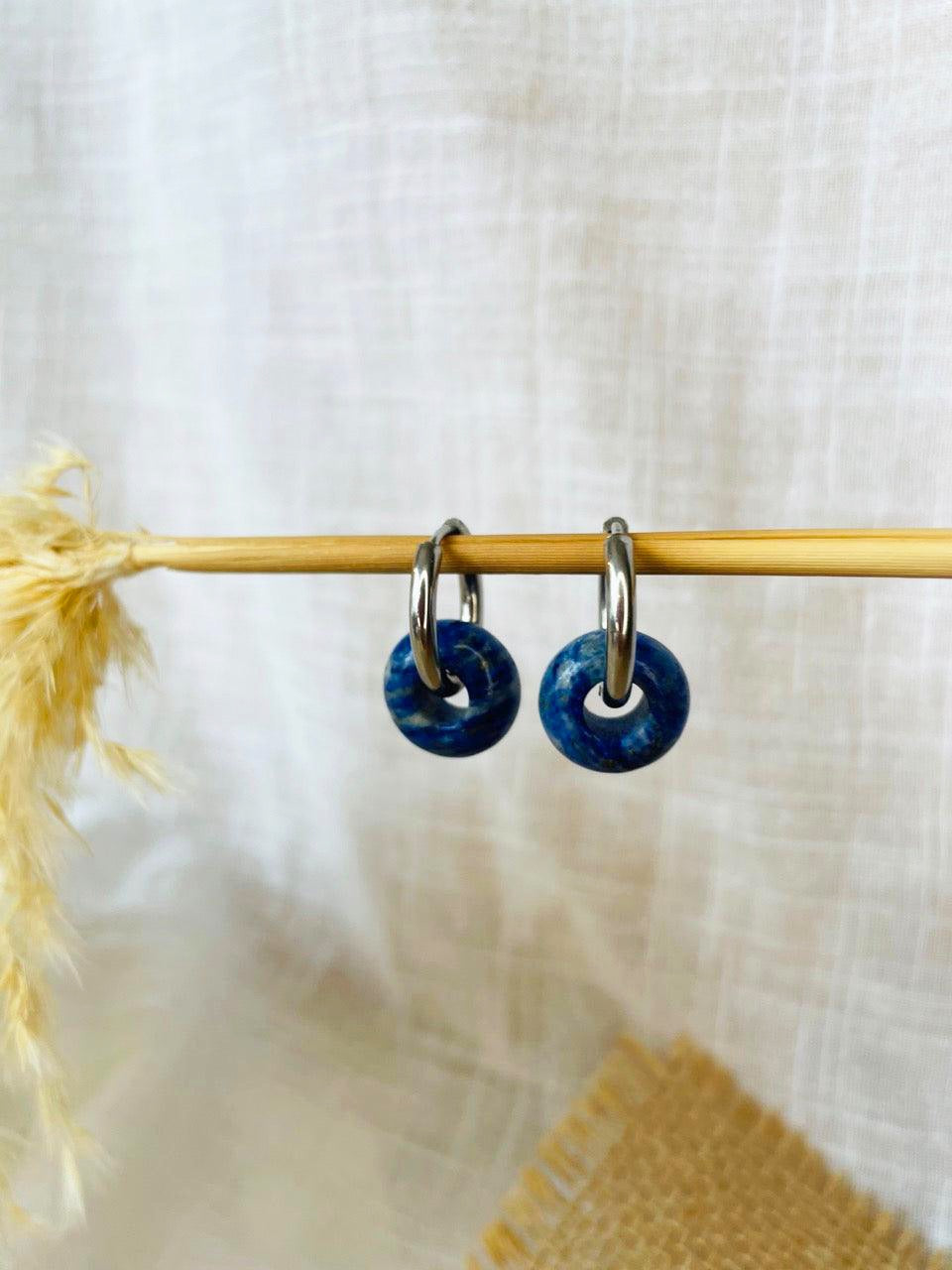 Boucles d'oreille THELMA, avec pierre de Lapis-Lazuli, exposées sur un fond en lin.