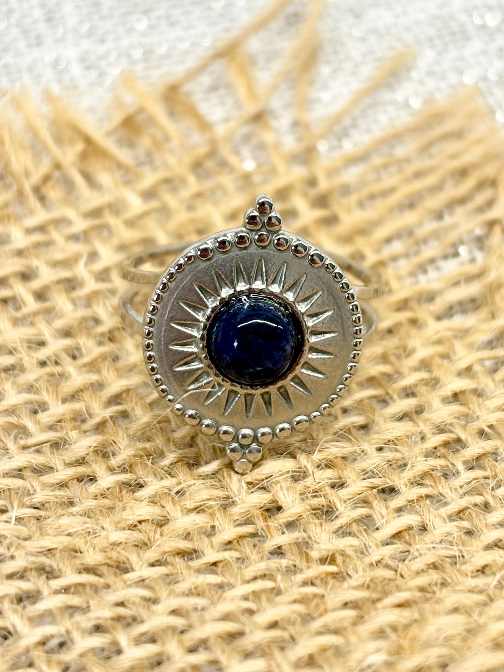 Bague ZÉLIE en acier inoxydable argent et pierre de Sodalite, exposé sur de la toile de jute et un fond en lin.