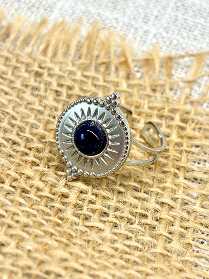 Gros plan de la Bague ZÉLIE en acier inoxydable argent et pierre de Sodalite, exposé sur de la toile de jute et un fond en lin.