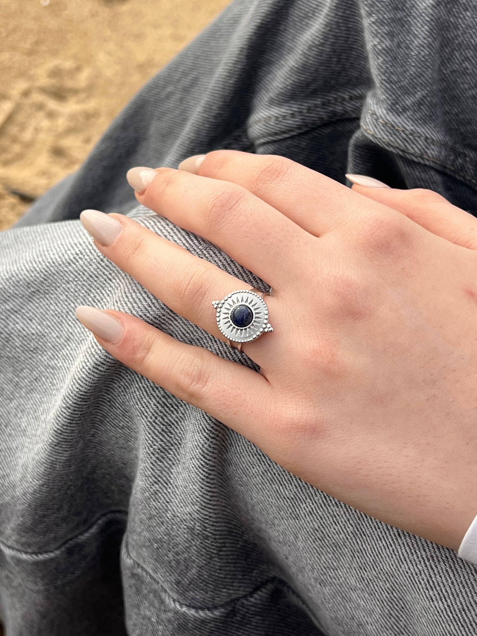 Bague ZÉLIE en acier inoxydable argent et pierre de Sodalite, porté par une femme sur la plage.