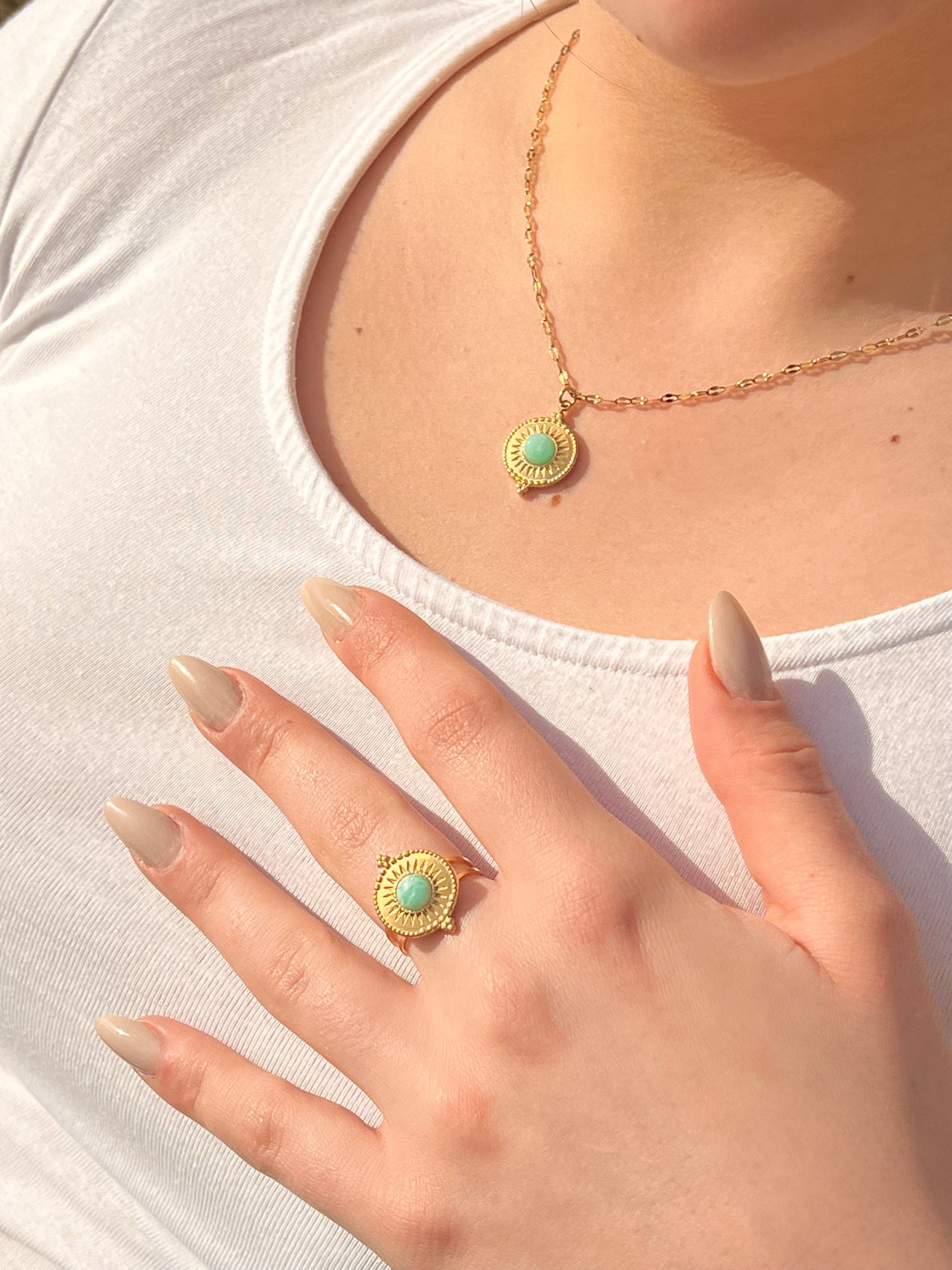 Collier et bague ZÉLIE en acier inoxydable doré avec pierre d'amazonite, porté par une femme dans des rochers