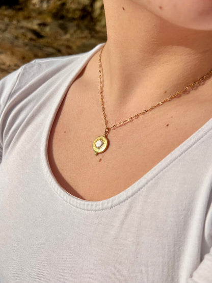 Collier ZÉLIE en acier inoxydable doré et pierre de Howlite, porté par une fille dans des rochers. 