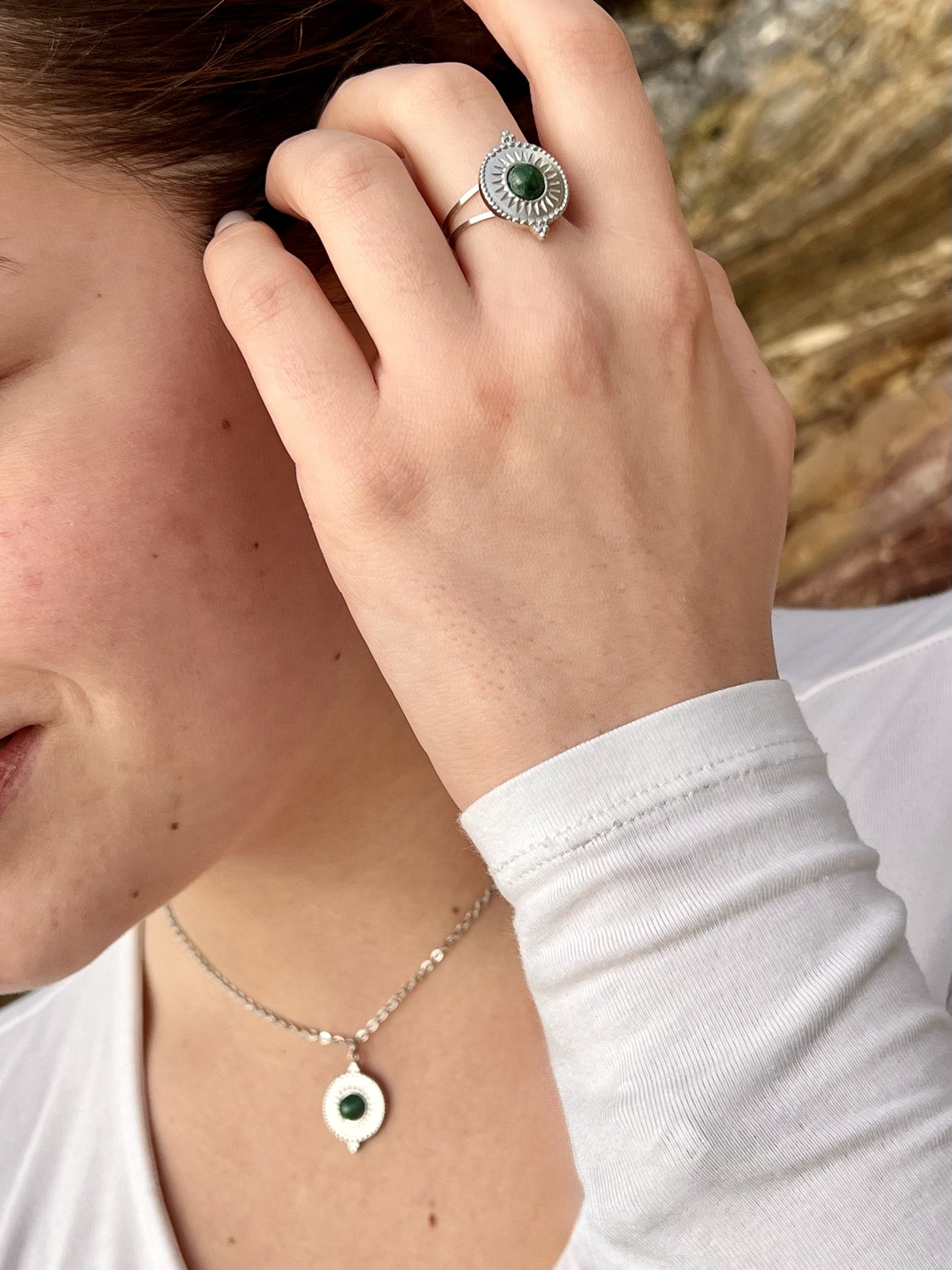 Collier ZÉLIE en acier inoxydable argent et pierre de Malachite, porté par une fille dans les rochers