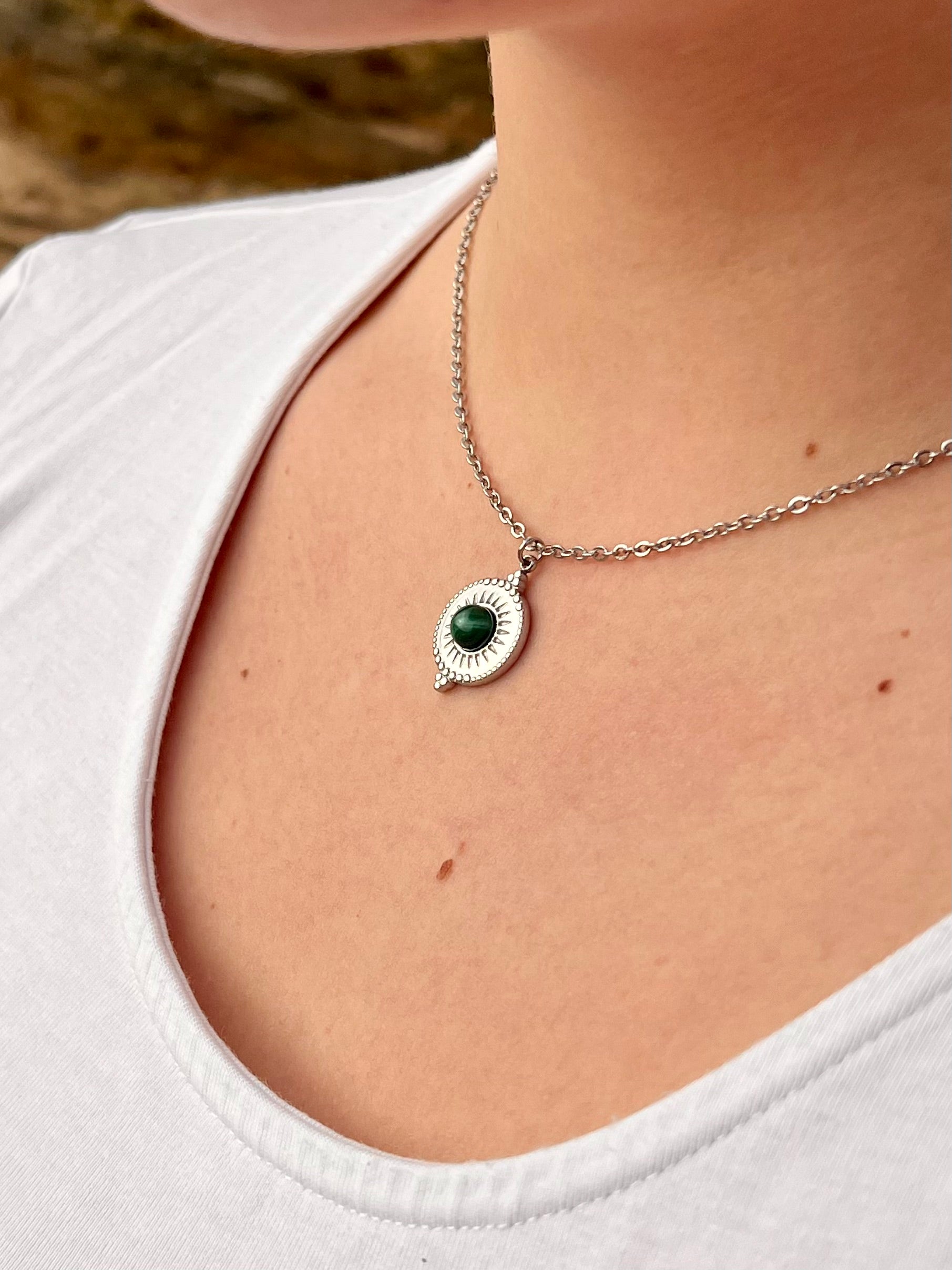 Collier ZÉLIE en acier inoxydable argent et pierre de Malachite, porté par une fille dans les rochers
